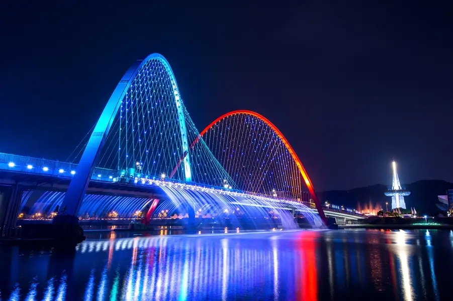 Thuyền đi qua một cây cầu rực rỡ trong tour đêm Singapore